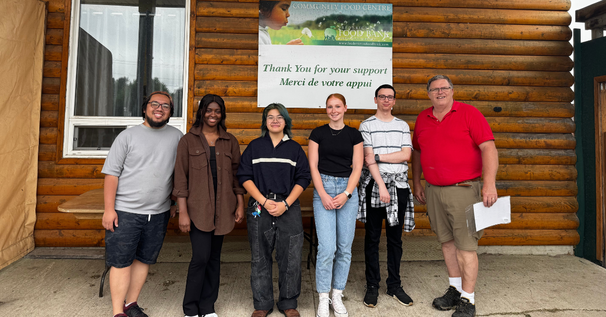 Group of 6 individuals standing in front of a sign that says "Community Food Centre: Thank you for your support."